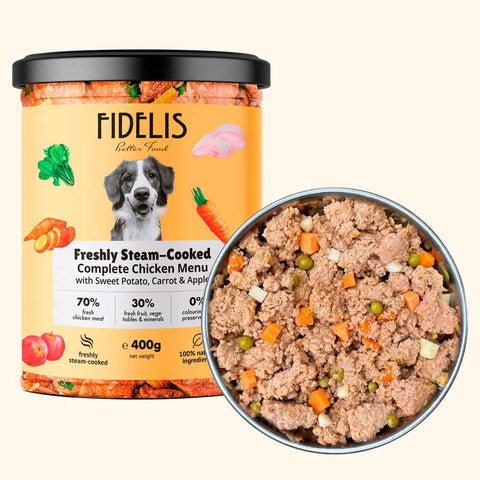 A jar of Fidelis freshly steam cooked complete chicken with sweet potato, carrot and apple dog food with a bowl of the food to it's right on a cream background