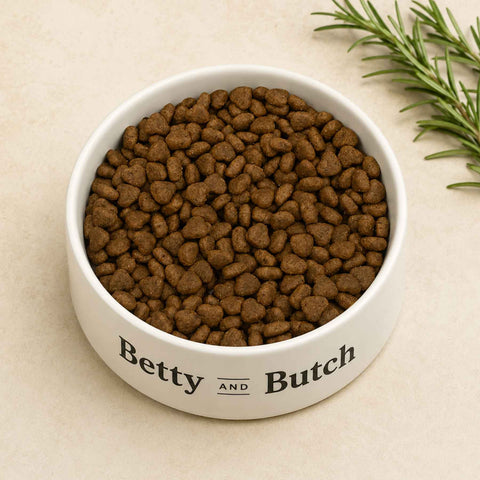 White bowl with peptide hydrolysed dog food labeled 'Betty and Butch' on a beige background